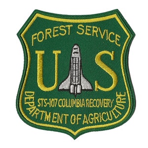 May include: A green and yellow embroidered patch with the words "Forest Service US Department of Agriculture" and the text "STS-107 Columbia Recovery". A white space shuttle is in the center of the patch.