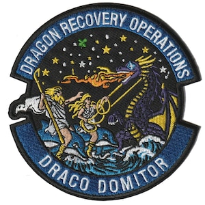 Könnte beinhalten: Ein runder bestickter Aufnäher mit einem violetten Drachen, der Feuer auf zwei in weiße Gewänder gekleidete Figuren auf blauen Wellen speit. Der Text DRAGON RECOVERY OPERATIONS und DRACO DOMITOR ist in Weiß auf schwarz-blauem Grund gestickt.