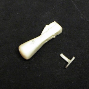 May include: A white plastic model of a rocket engine with a separate white plastic stand.