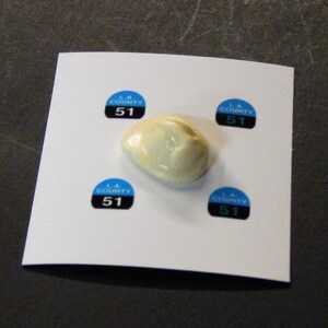 May include: Four blue and black stickers with the text "LA COUNTY 51" on a white surface. A white, round, soft object is in the center of the stickers.
