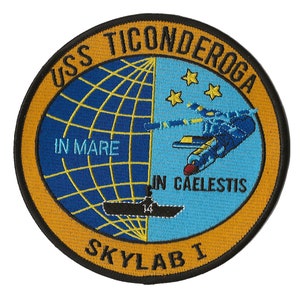 May include: A circular embroidered patch with a yellow border and black text. The text reads "USS TICONDEROGA SKYLAB I". Inside the circle is a blue and yellow globe with a space shuttle orbiting above it. The text "IN MARE IN CAELESTIS" is also visible.