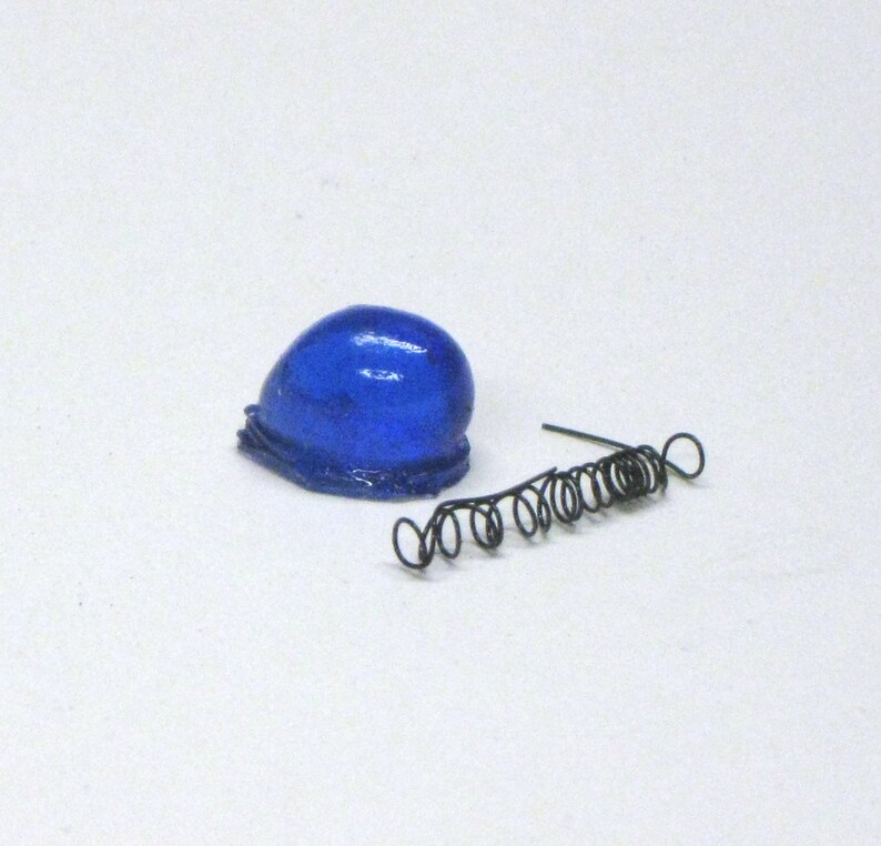 Puede incluir: Un objeto azul, redondo y gelatinoso con un muelle de espiral negro a su lado.