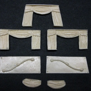 May include: Set of six white plastic pieces for model building. The pieces include two sets of window curtains, two curved pieces, and two half-circle pieces.