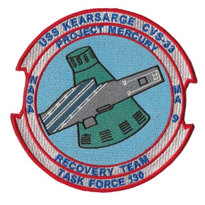 May include: A circular patch with a red, white, and blue design. The patch features a green and gray spacecraft with the text "USS KEARSARGE CVS-32 PROJECT MERCURY NASA RECOVERY TEAM TASK FORCE 130".