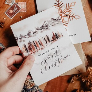 Aquarelle d'hiver dans une cabane | Pour les Fêtes de Noël confortable de Zazzle.be Liste d'envies Vous avez des idées ? Paysage peint de pins de montagne du lac gelé | Carte de voeux écologique