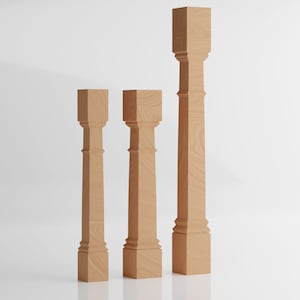 May include: Three wooden balusters in different sizes, all with a square top and a decorative, fluted design. The balusters are made of light brown wood and are standing on a white surface.