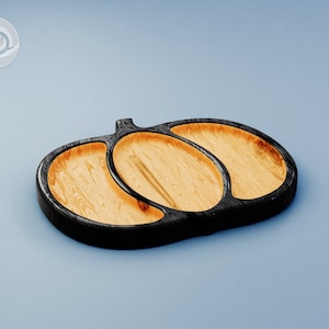 May include: A wooden serving tray shaped like a pumpkin with three separate compartments. The tray is black with a natural wood finish.