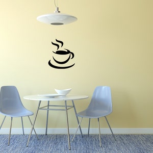 May include: A black coffee cup and saucer wall decal with steam rising from the cup, above a white table with two light blue chairs and a white bowl on the table. The table and chairs are on a blue rug in front of a yellow wall.