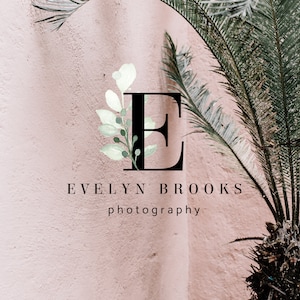 Puede incluir: Una letra E negra con un diseño floral de acuarela en tonos verdes y blancos. El texto "EVELYN BROOKS photography" está debajo de la letra.