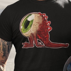 May include: Black t-shirt with a graphic print of a cartoon eyeball with red veins and legs.