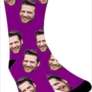 May include: A pair of purple socks with a repeated pattern of a man's face. The socks are black at the toes and heels.