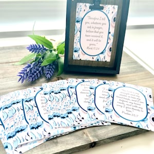 May include: A set of eight inspirational cards with watercolor floral designs and bible verses. The cards feature blue, pink, and white colors. The verses include "The Lord is my strength and my shield" and "Therefore I tell you, whatever you ask in prayer, believe that you have received it, and it will be yours."