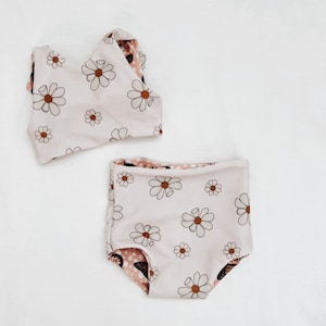 Peut inclure: Un maillot de bain deux pi&egrave;ces pour b&eacute;b&eacute;s et tout-petits. Le haut est un d&eacute;bardeur blanc &agrave; imprim&eacute; marguerite marron. Le bas est blanc avec un imprim&eacute; marguerite marron et un imprim&eacute; papillon marron &agrave; l'int&eacute;rieur.