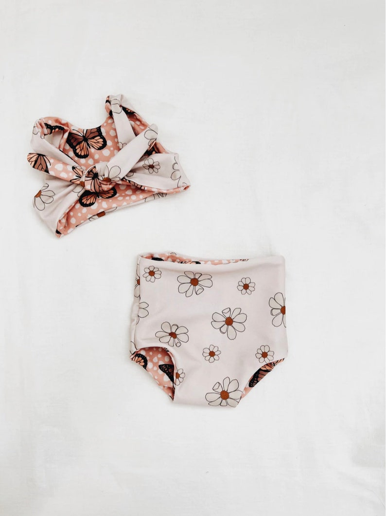 Peut inclure: Un maillot de bain deux pi&egrave;ces pour enfant. Le haut est de style halter avec un imprim&eacute; papillon et pois. Le bas est de style taille haute avec un imprim&eacute; marguerite.