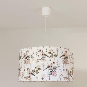 Può includere: Lampada da soffitto bianca con un paralume a tamburo bianco con un motivo di uccelli marroni e rosa e disegni floreali.