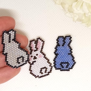 May include: Three beaded bunny charms, one white with pink ears, one white with black ears, and one blue with black ears.