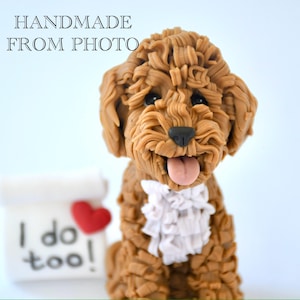 May include: A brown dog figurine with a white ruffled collar and a pink tongue sticking out. The figurine has the text "HANDMADE FROM PHOTO" above it. A small white block with the text "I do too!" and a red heart is to the left of the dog.