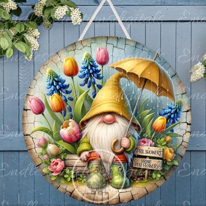 May include: A gnome wearing a yellow hat and holding an umbrella sits in a garden with blue and purple flowers, green leaves, and pink tulips. A sign reads "April Showers Bring May Flowers".
