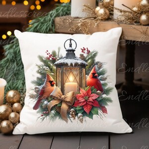 May include: White throw pillow with a winter scene featuring a lantern, two cardinals, and a poinsettia. The lantern is lit and has a candle inside. The cardinals are perched on branches and the poinsettia is in bloom.