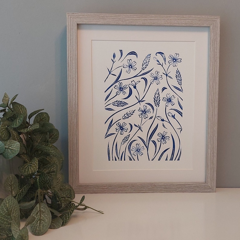 May include: A framed print of a blue floral design on a white background. The design features stylized flowers and leaves.
