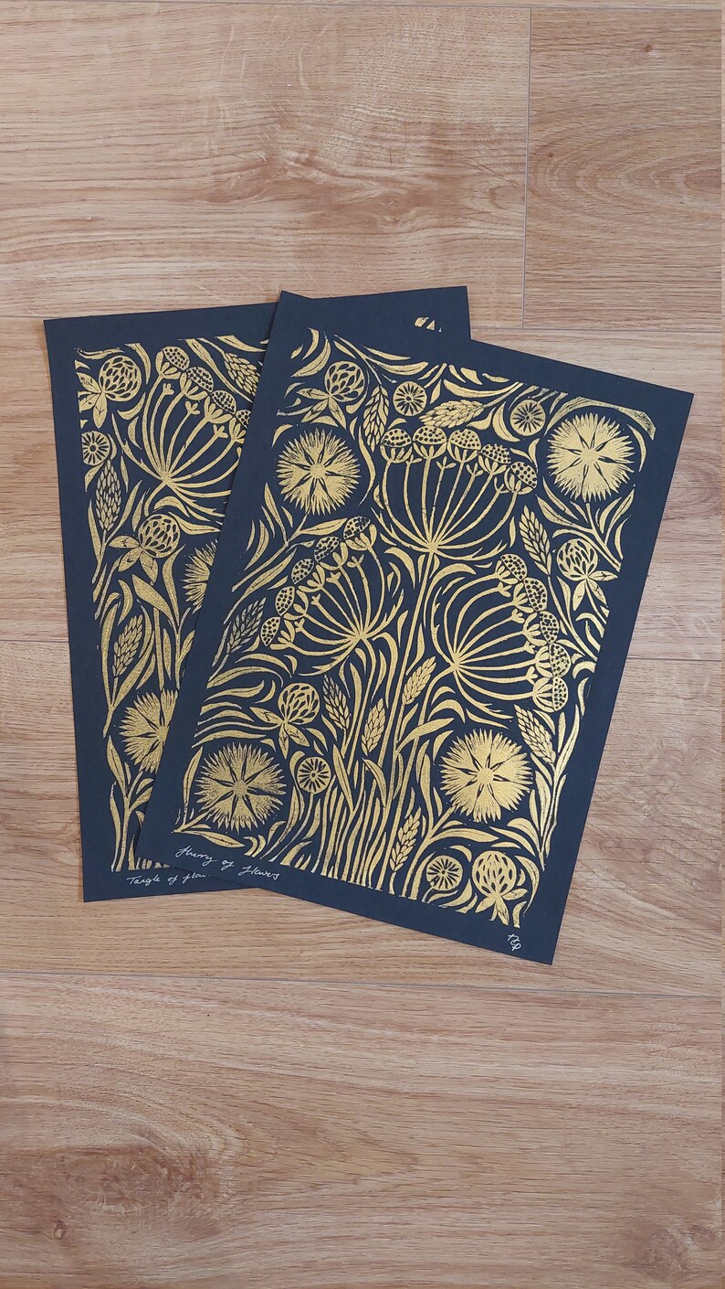 May include: Two art prints with gold floral designs on a dark blue background. The prints feature intricate botanical patterns, including flowers and foliage. The text "Temple of Flowers" and artist's signature are visible.