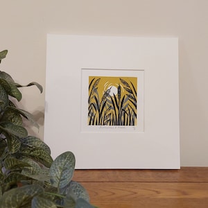 May include: A framed print of a yellow and black illustration of reeds and a bird in a yellow field. The print is titled "Eustmahes & Reeds" and is signed with the number 15.