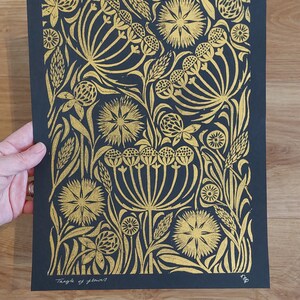 May include: A black and gold floral art print featuring a detailed botanical design. The artwork showcases a variety of stylized flowers and foliage in a repeating pattern. The text "Tangle of flowers" is visible at the bottom.
