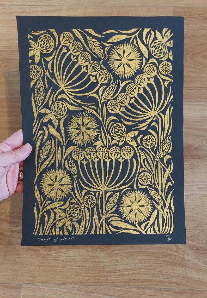 May include: A black and gold floral art print featuring a detailed botanical design. The artwork showcases a variety of stylized flowers and foliage in a repeating pattern. The text "Tangle of flowers" is visible at the bottom.