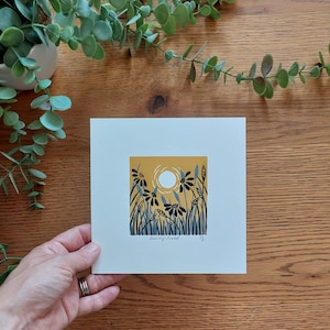 May include: A print of a yellow field with blue flowers and a white sun. The print is titled "Daisy Field" and signed by the artist.
