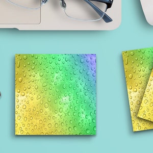 May include: Four black paper clips shaped like a cat, a laptop computer with a pair of glasses on the keyboard, a white computer mouse, a cup of coffee, a bouquet of blue and white flowers, and three colorful square coasters with a water droplet pattern.