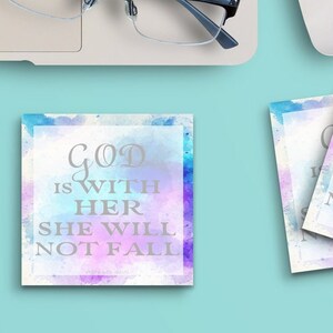 May include: Four square coasters with a watercolor background in shades of blue, pink, and purple. The coasters feature the text "God is with her, she will not fall" in a silver metallic font.
