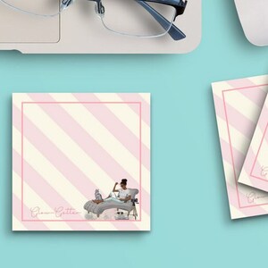 May include: A set of four pink and white striped notepads with the text "Glam Getter" printed on each notepad. The notepads feature a woman sitting on a chaise lounge with a cat.