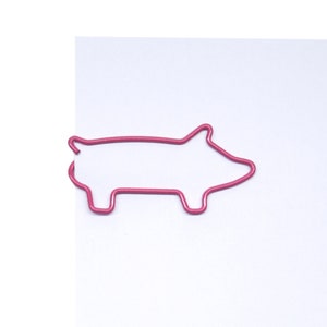 May include: A pink metal paperclip shaped like a pig.