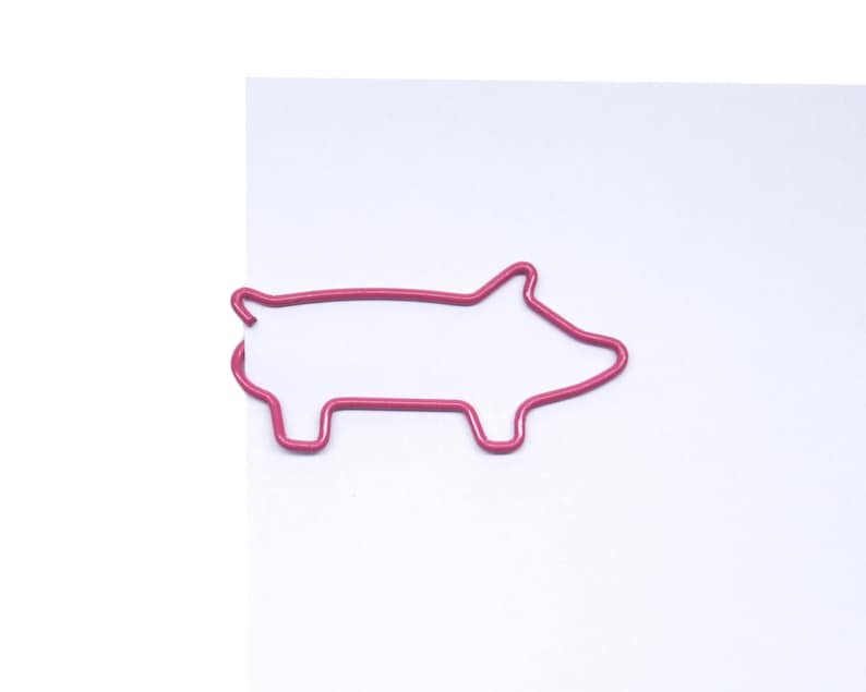 May include: A pink metal paperclip shaped like a pig.
