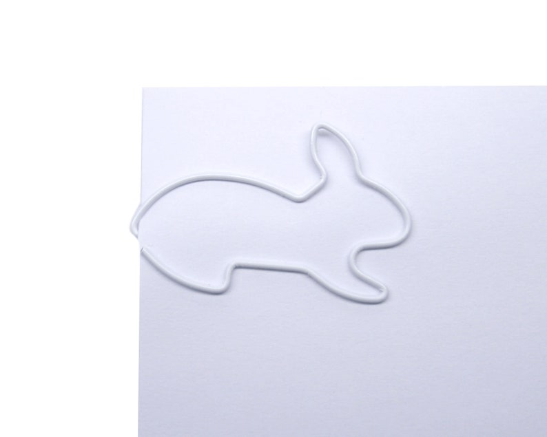 May include: White metal paper clip shaped like a rabbit.