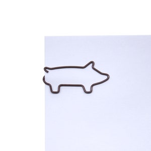 May include: A brown metal paperclip shaped like a pig.