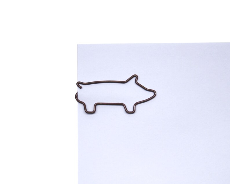 May include: A brown metal paperclip shaped like a pig.