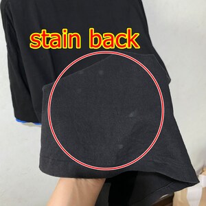May include: Black long-sleeve shirt with a stain on the back. The stain is circled in red.