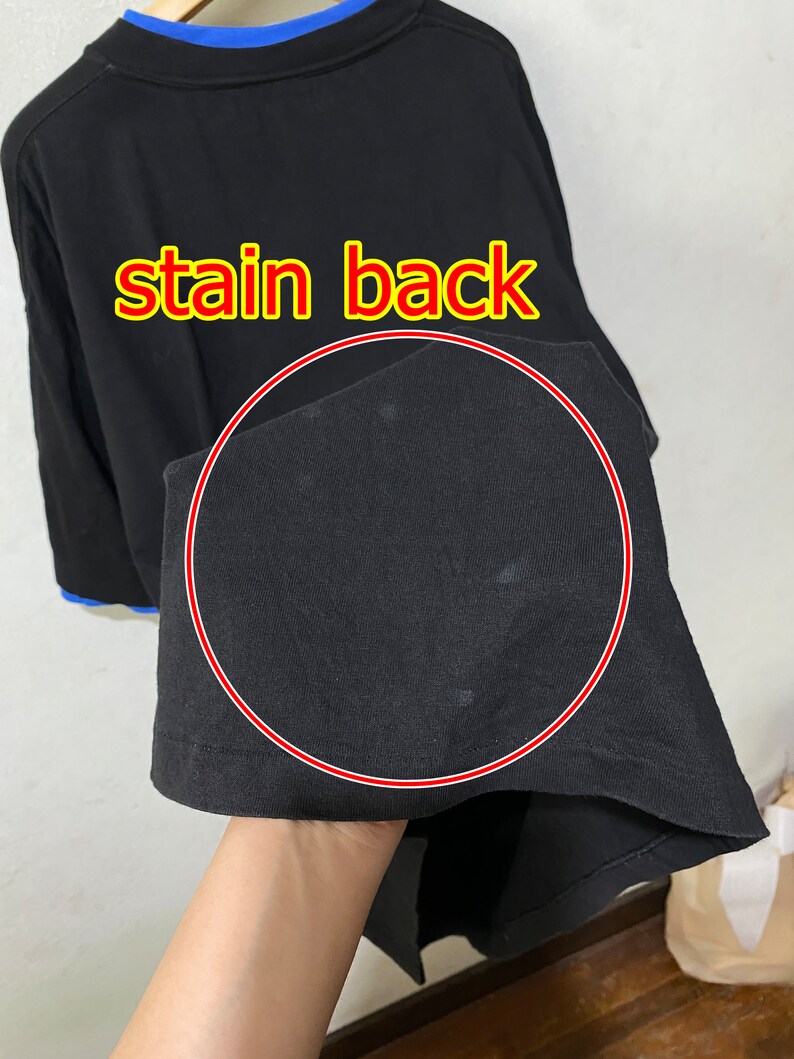 May include: Black long-sleeve shirt with a stain on the back. The stain is circled in red.