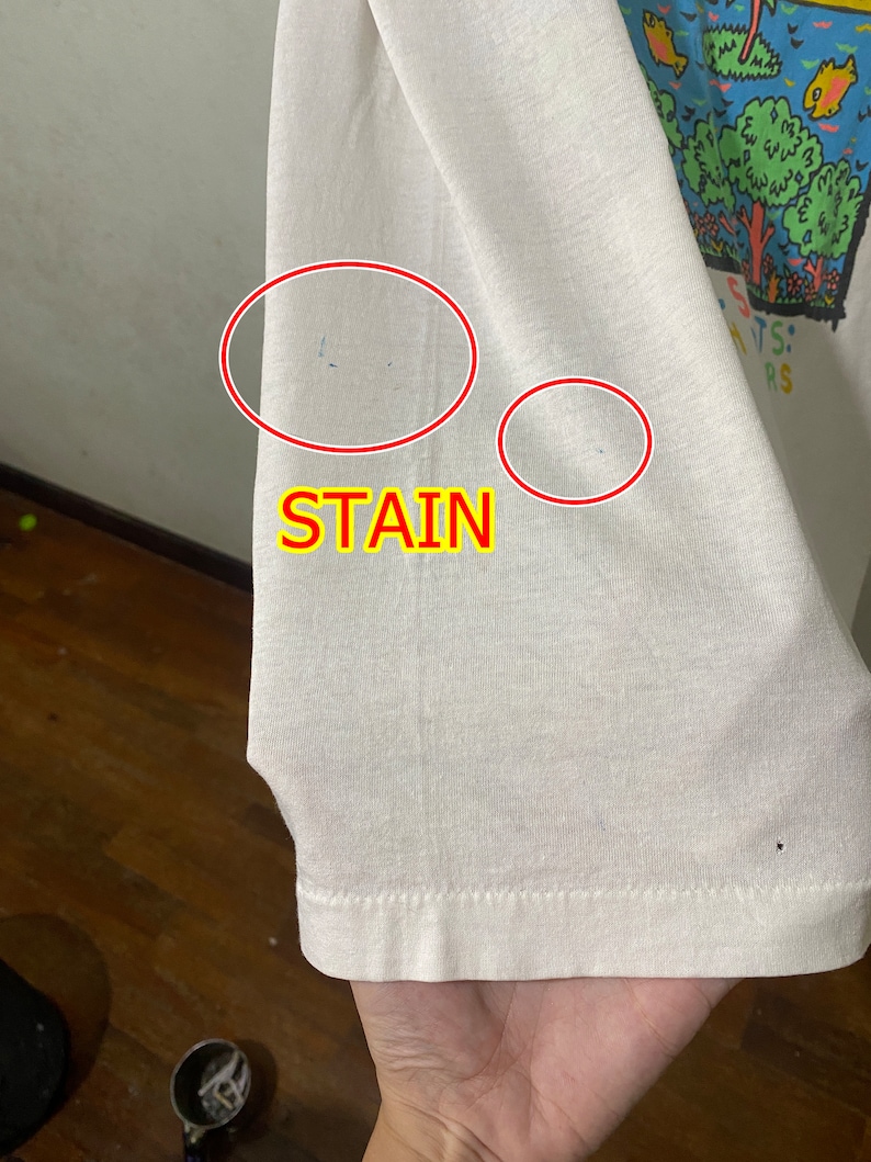 May include: White t-shirt with a colorful graphic print and the text "ANTS: " and "RS". The shirt has two small stains on the sleeve.