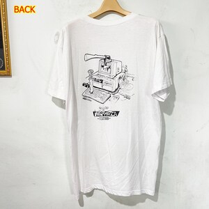 May include: White t-shirt with a black and white graphic of a vintage computer with an axe, keyboard, and the text "ACUTED INFORMATICA - REBOOT". The shirt is hanging on a wooden hanger.