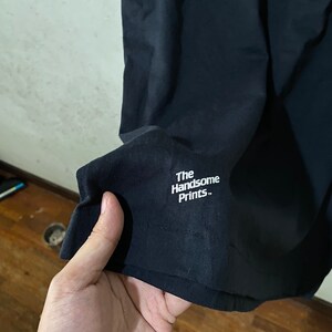 以下が含まれることがあります： 「The Handsome Prints.」という白い文字が書かれた黒いTシャツ