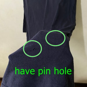 May include: A dark blue t-shirt with two pinholes. The text "have pin hole" is written in green below the pinholes.