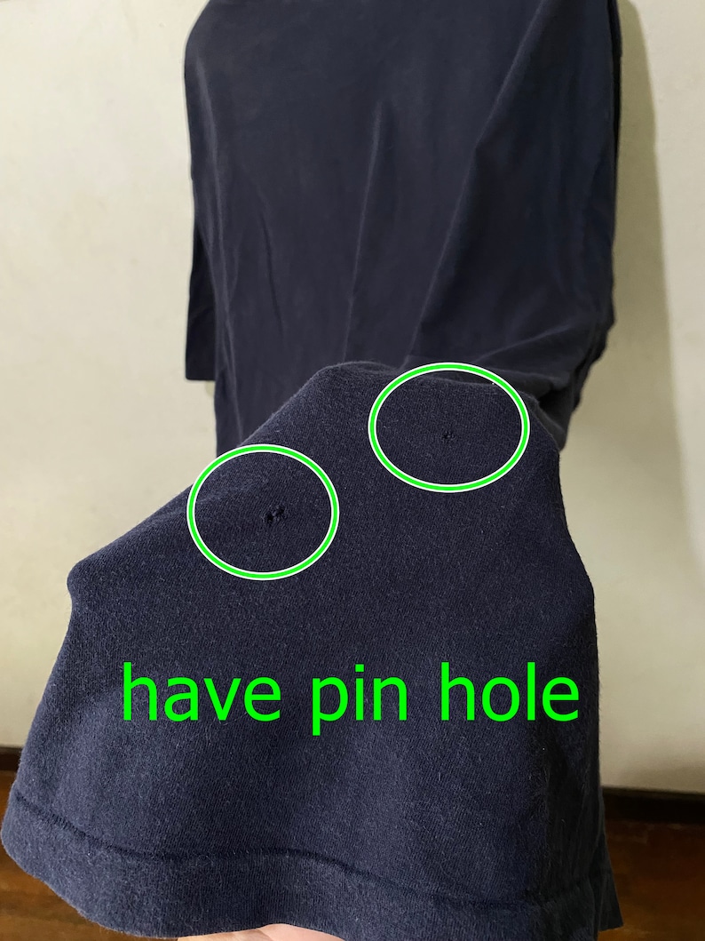 May include: A dark blue t-shirt with two pinholes. The text "have pin hole" is written in green below the pinholes.