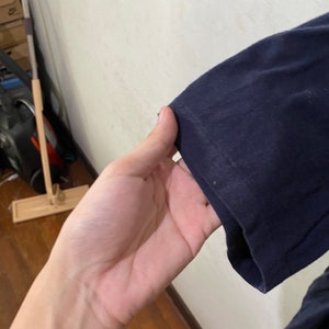 May include: Close-up of the navy blue sleeve of a long-sleeved shirt. The sleeve is folded over and the fabric is smooth.