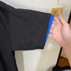 May include: Black short-sleeved t-shirt with a blue trim on the sleeves.