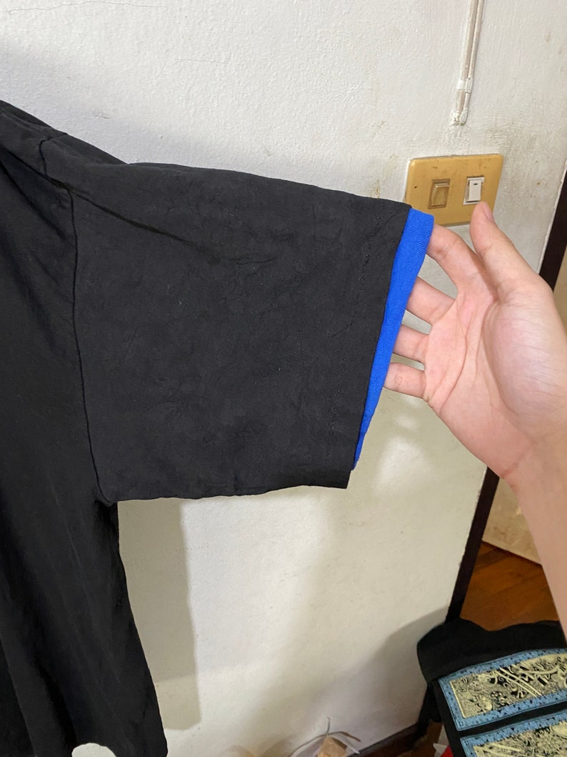 May include: Black short-sleeved t-shirt with a blue trim on the sleeves.