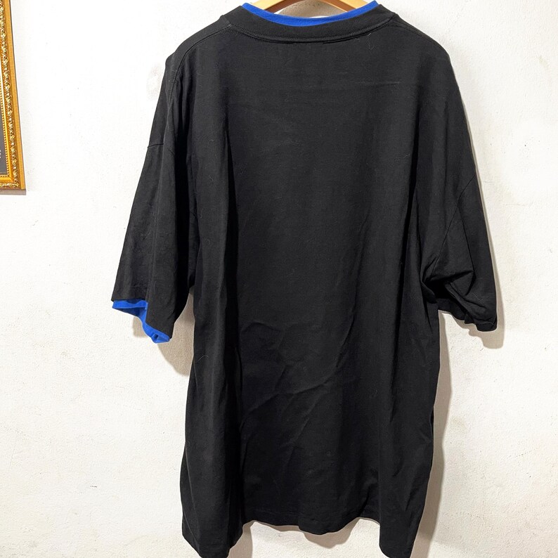 May include: Black short-sleeved t-shirt with a blue trim around the neckline.