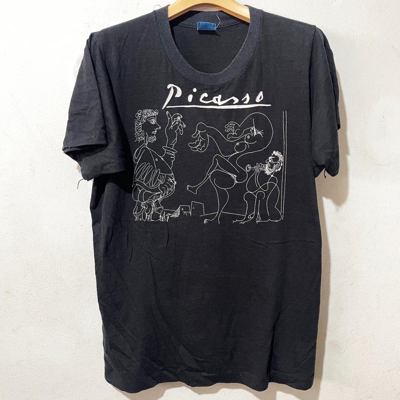 May include: A black t-shirt with a white line drawing of a Picasso painting and the word 'Picasso' printed on the front.