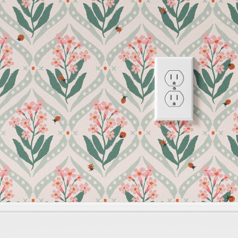 Pode incluir: Papel de parede floral com flores cor-de-rosa, folhas verdes e joaninhas sobre um fundo rosa claro. O design inclui um padr&atilde;o repetitivo de flores e folhas estilizadas, com uma tomada el&eacute;trica branca.